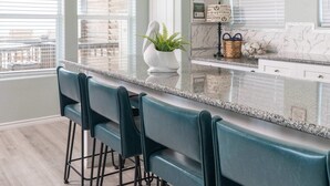 A kitchen with a bar area, a potted plant, and a decorative wall piece. - Beachfront • Perfect for Groups (Bolivar Peninsula)