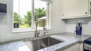 Eine Küche mit Granit Arbeitsplatte, Spüle aus Edelstahl und einem Fenster mit Blick auf Grünflächen.