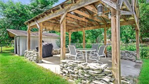 Ein überdachter Patio-Bereich mit Steinwänden, einem Grill und Sitzgelegenheiten im Freien.