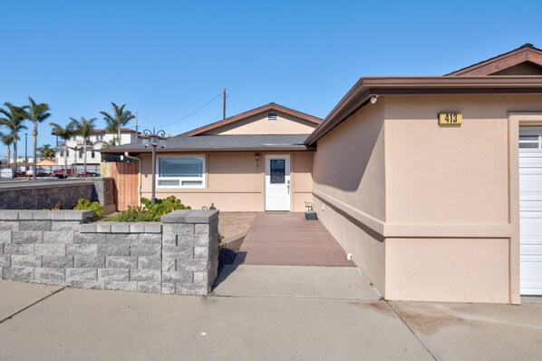 Une maison de plain-pied à l’extérieur beige, avec une porte d’entrée et une porte de garage.
