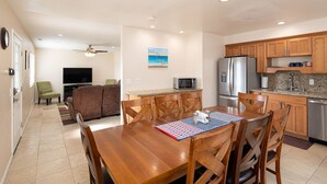 Una cocina amplia con armarios de madera, un refrigerador de acero inoxidable y un comedor con mesa y sillas de madera.