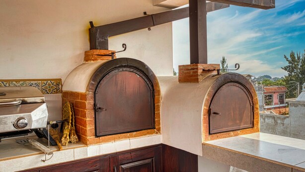 A kitchen with two wood-fired ovens, a grill, and a view of the city.
