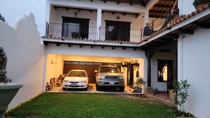 A two-story house with a garage containing two vehicles, a white car and a silver truck.