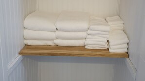 Un área de almacenamiento con dos estantes de madera, cada uno con toallas blancas dobladas ordenadamente.