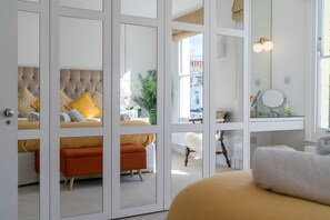 A bedroom with a bed, a nightstand, a mirror, and a window. - Stylish apartment with two beds in Shepherd’s Bush (London)