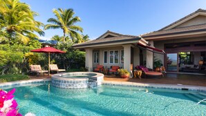 A swimming pool with a hot tub, surrounded by outdoor furniture and palm trees.