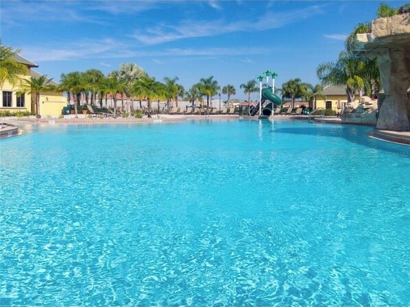 Relax by the pool surrounded by palm trees and lounge chairs.