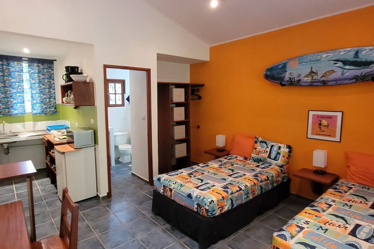 A compact bedroom with a bed, bedside tables, and a small desk area.
