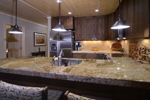 A kitchen with granite countertops, stainless steel appliances, and wooden cabinets. - Evergreen Condo | Walk to Lifts | Shared Hot Tub | Very Convinient (Mt. Crested Butte)