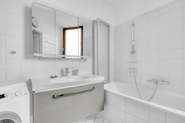 Une salle de bain moderne avec un lavabo blanc, un miroir et une douche.