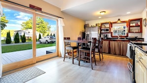 A modern kitchen with a dining area, large windows, and a view of the outside.