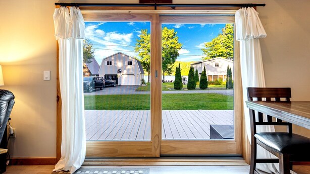 A room with a sliding glass door leading to a deck, a wooden table, and a chair.