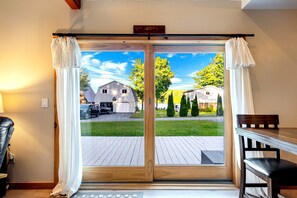 A room with a sliding glass door leading to a deck, a wooden table, and a chair.