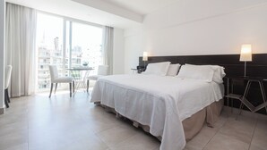 A hotel room with a large bed, a desk, and a chair. There is a window with curtains, and the room has a modern design. - Beautiful Studio in Palermo Hollywood (CABA)