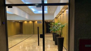 A hotel lobby with a glass door entrance, a tiled floor, and potted plants. - Beautiful Studio in Palermo Hollywood (CABA)