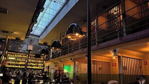 Eine mehrstöckige Bar mit Oberlichter, mehreren hängenden Lampen und einem grün beleuchteten Innenraum.