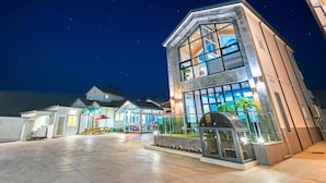 A modern hotel with a spacious outdoor area, large windows, and a covered seating area. - Gyeongju Cheongun28 Kids Poolvilla (Gyeongju)