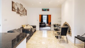 A spacious living area with a modern kitchen, a dining area with a fireplace, and a view of the outdoors. - Luxury Town House (Bolton)