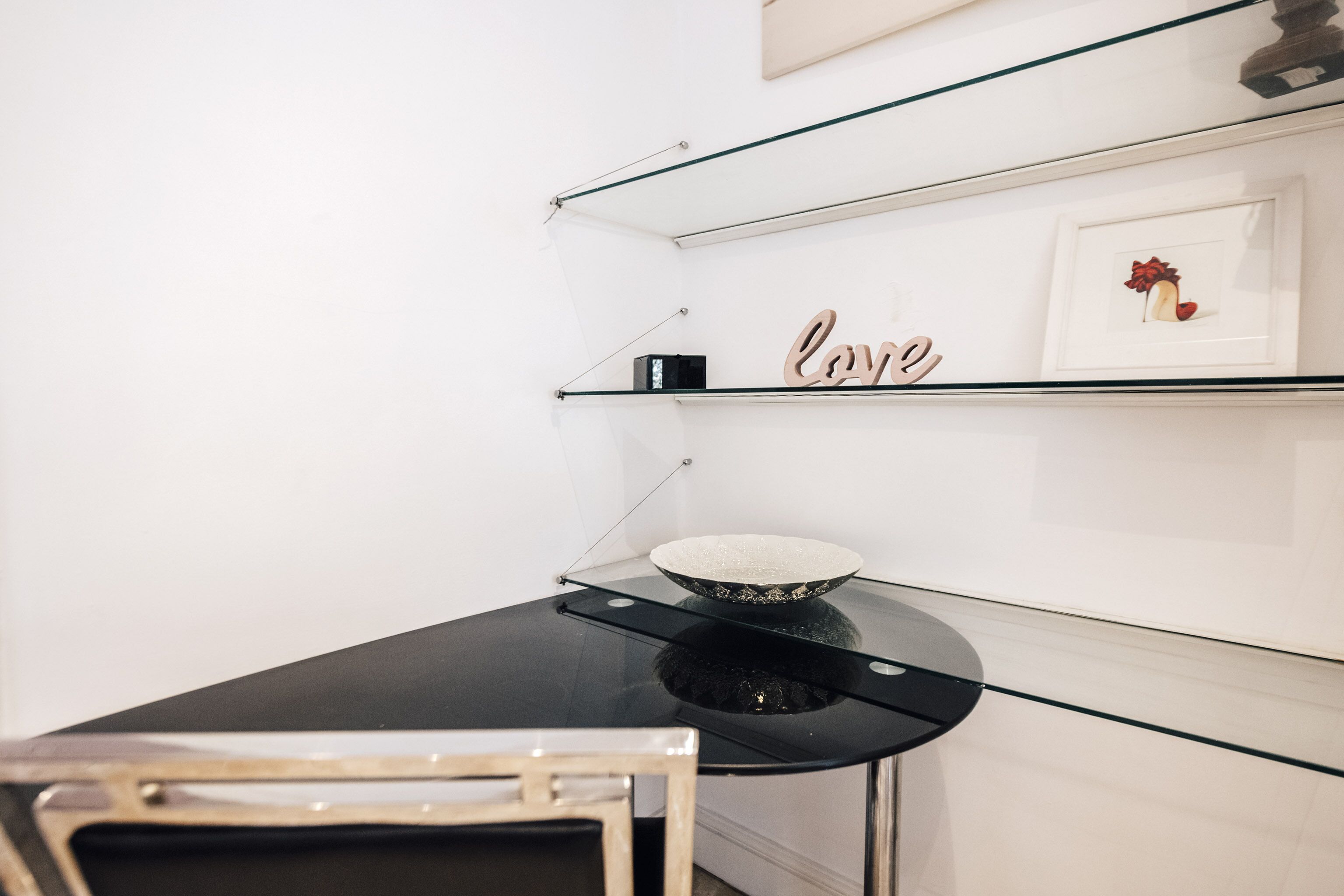 Una cocina moderna con encimera negra, un cuenco y una estantería con un cuadro enmarcado y la palabra 'Love'.