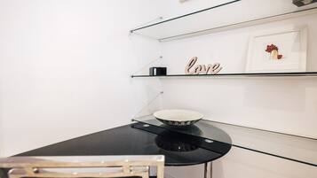 Una cocina moderna con encimera negra, un cuenco y una estantería con un cuadro enmarcado y la palabra 'Love'.