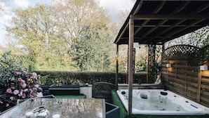 A hot tub and a table with candles in a garden setting. - Luxury Town House (Bolton)