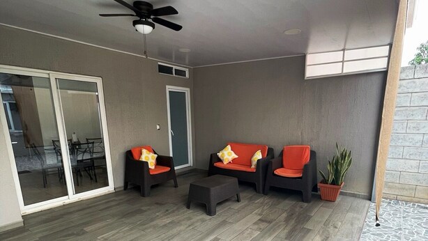 A covered patio area with a ceiling fan, a sliding glass door leading to a dining area, and a potted plant.