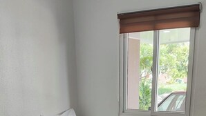 A small, clean room with two single beds, a window with a view of the outdoors, and a white wall.
