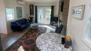 A living room with a blue sofa, a round marble table, and a colorful rug.