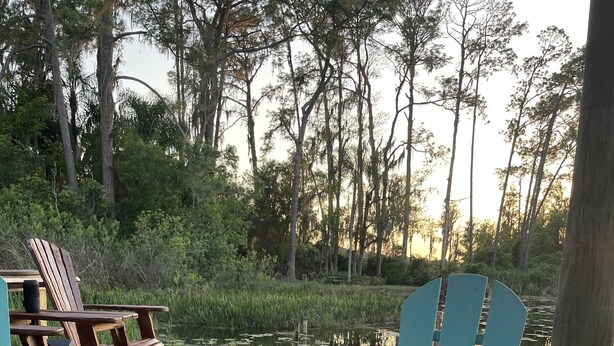 A wooden deck with a fire pit and two Adirondack chairs.