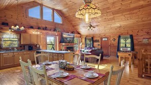A spacious wooden cabin with a dining area, kitchen, and living room.