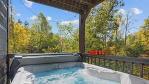 A hot tub on a wooden deck with a view of autumn trees.