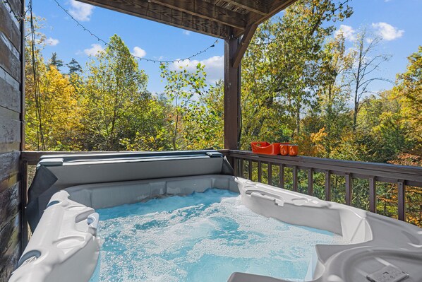 Ein Whirlpool auf einer Holzterrasse mit Blick auf Herbstbäume.