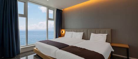 Una cama grande con vista al mar, una mesita de noche y una lámpara de pared.