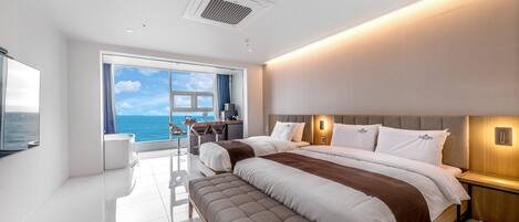 Una habitación de hotel moderna con una cama grande, un escritorio y vistas al océano.