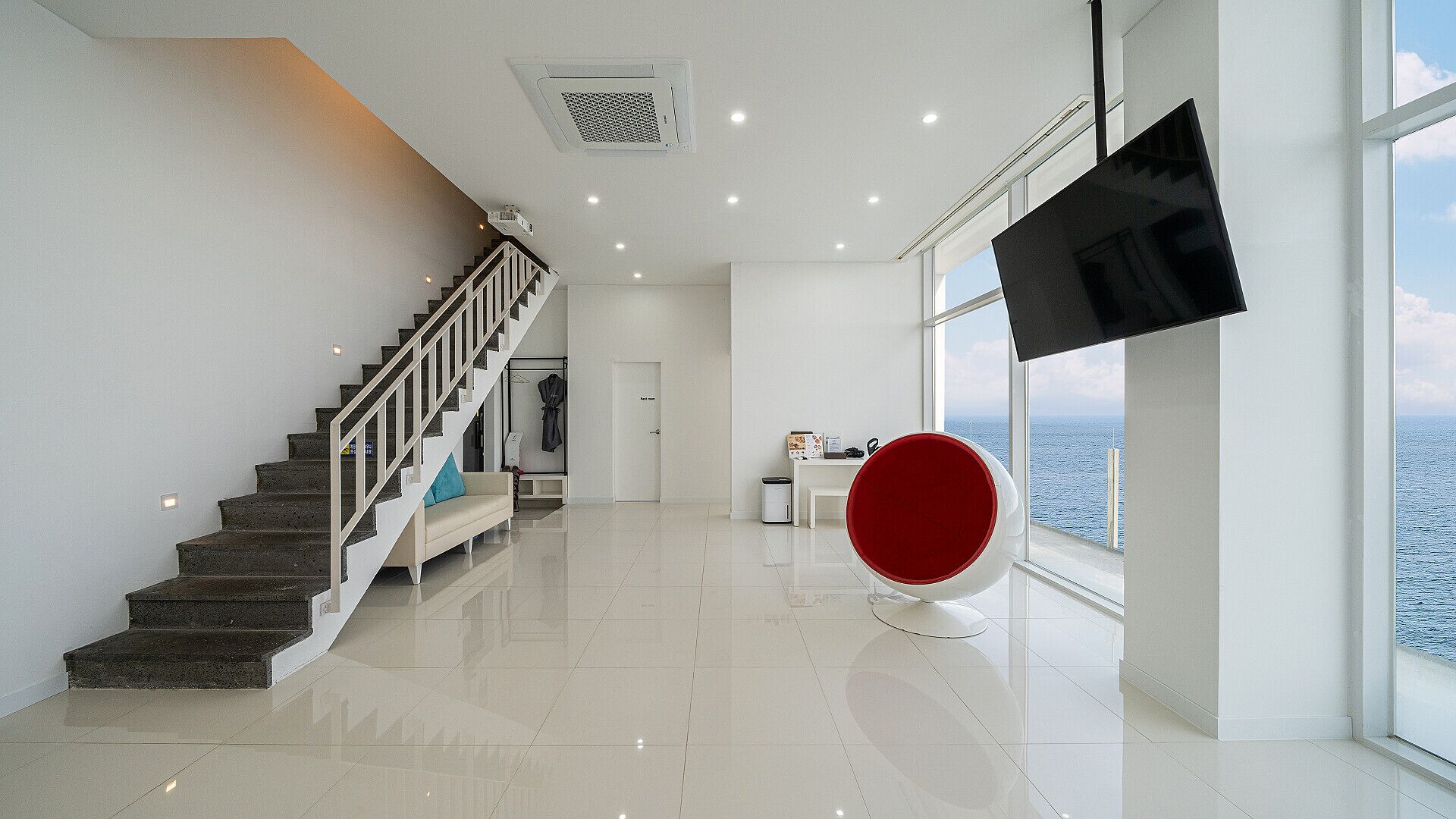 A spacious room with a staircase, a flat-screen TV, and a view of the sea.