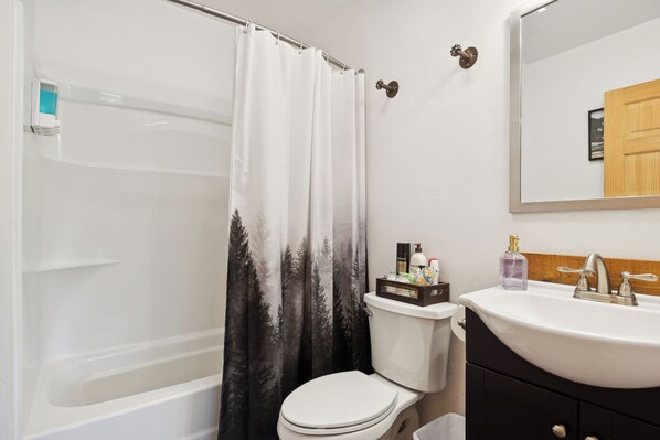 A bathroom with a bathtub, toilet, and sink. - Beargrass Cabin @ Explorer's Basecamp (Kalispell)
