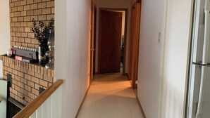 A narrow hallway with a brick wall on one side, a wooden railing, and a refrigerator on the other. - Lake Simcoe Getaway — Just 1 Hour from Toronto! Family cottage rarely offered! (Georgina)