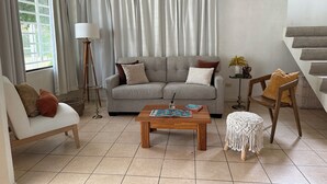 Un salon avec un canapé gris, une table basse en bois, un lampadaire et un escalier.