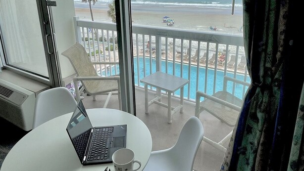 A hotel room with a balcony overlooking a beach and a pool. - A breathtaking oceanfront studio w/ a private balcony (Daytona Beach)