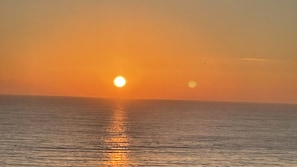 A sunset over a calm sea with a clear horizon. - A breathtaking oceanfront studio w/ a private balcony (Daytona Beach)