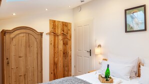 A bedroom with a wooden wardrobe, a bed with white linens, a bedside table with a bottle and glasses, and a painting on the wall. - Apartment 'Xaver' with Shared Garden, Balcony, and Wi-Fi (Rottenbuch)