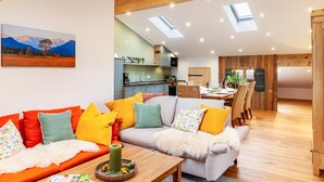 A modern living room with a sofa, a dining area, and a kitchen. - Apartment 'Xaver' with Shared Garden, Balcony, and Wi-Fi (Rottenbuch)