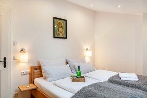 A bedroom with a bed, bedside lamps, a wall-mounted picture, and a bedside table with a remote control.
