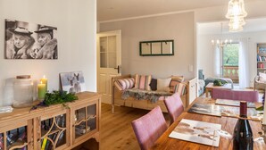 Una sala acogedora con una mesa de comedor de madera, un sofá y una estantería.