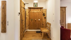 Una puerta de madera con un escudo, un banco y una pequeña mesa en un pasillo.