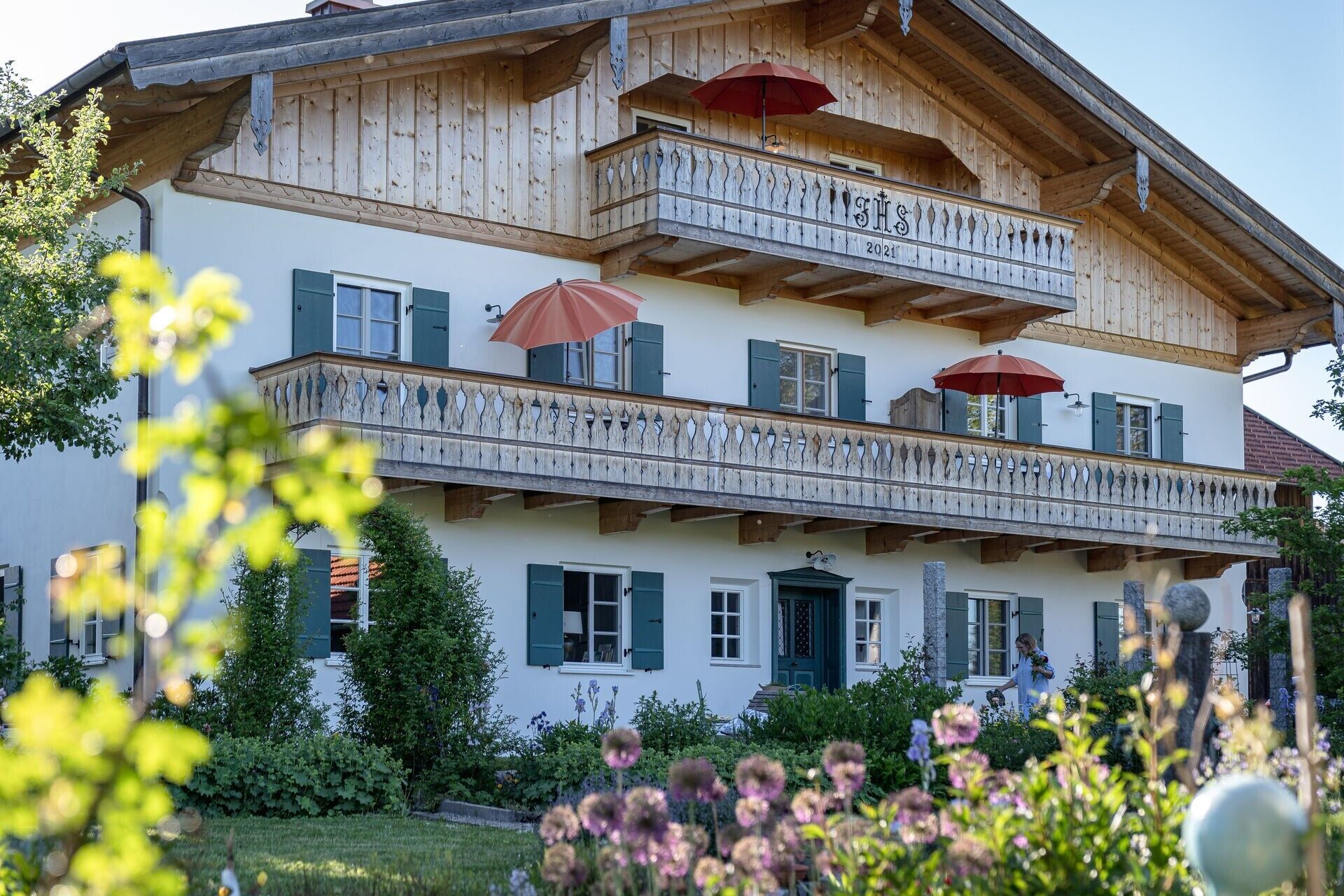 Ein zweistöckiges Gebäude mit Balkonen, einer Holzfassade und einem Garten im Vordergrund.