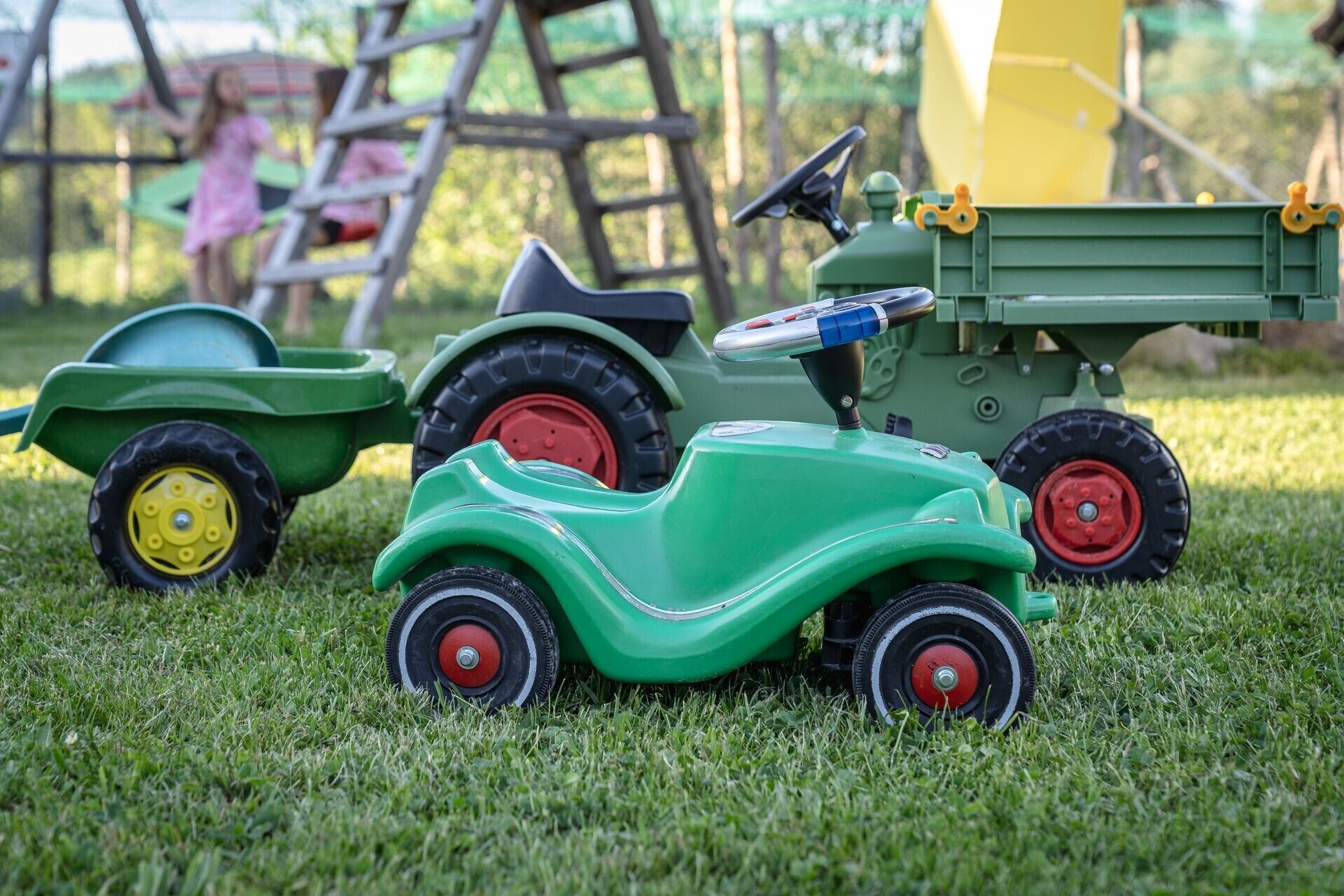A toy tractor and trailer on a grassy field.