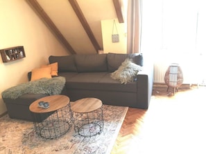A living room with a sofa, two round tables, a patterned rug, and a hanging bag. - Holiday Apartment 'Boven' at Timmeler Meer with Balcony and Wi-Fi (Timmel)