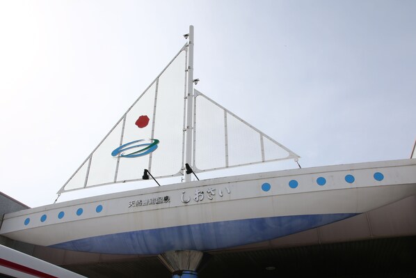 A building with a triangular roof structure, a red circular object on the peak, and a blue circular object below it.