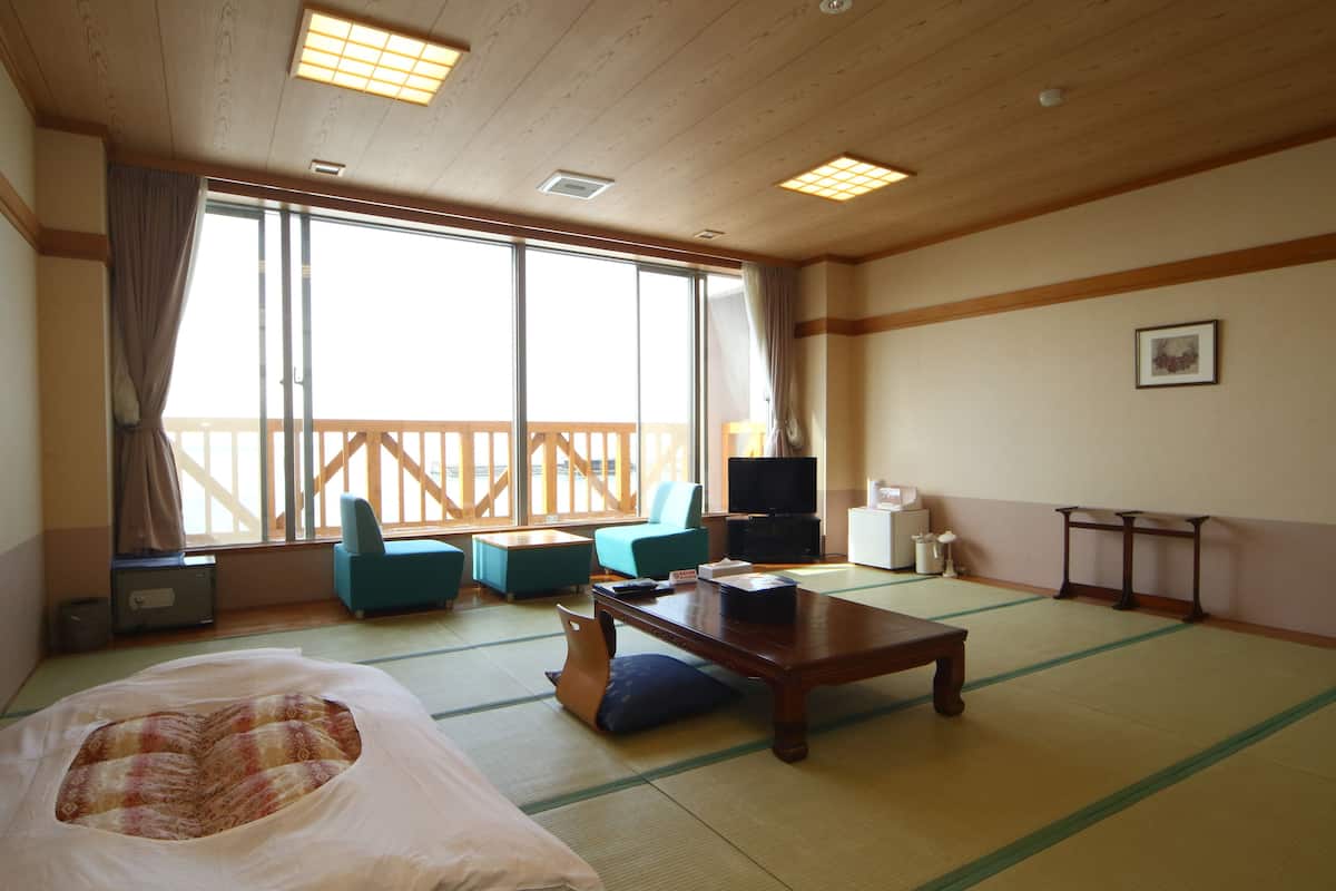 Ein traditioneller japanischer Raum mit Tatami-Boden, einem niedrigen Holztisch, einer Couch und einem Fernseher.